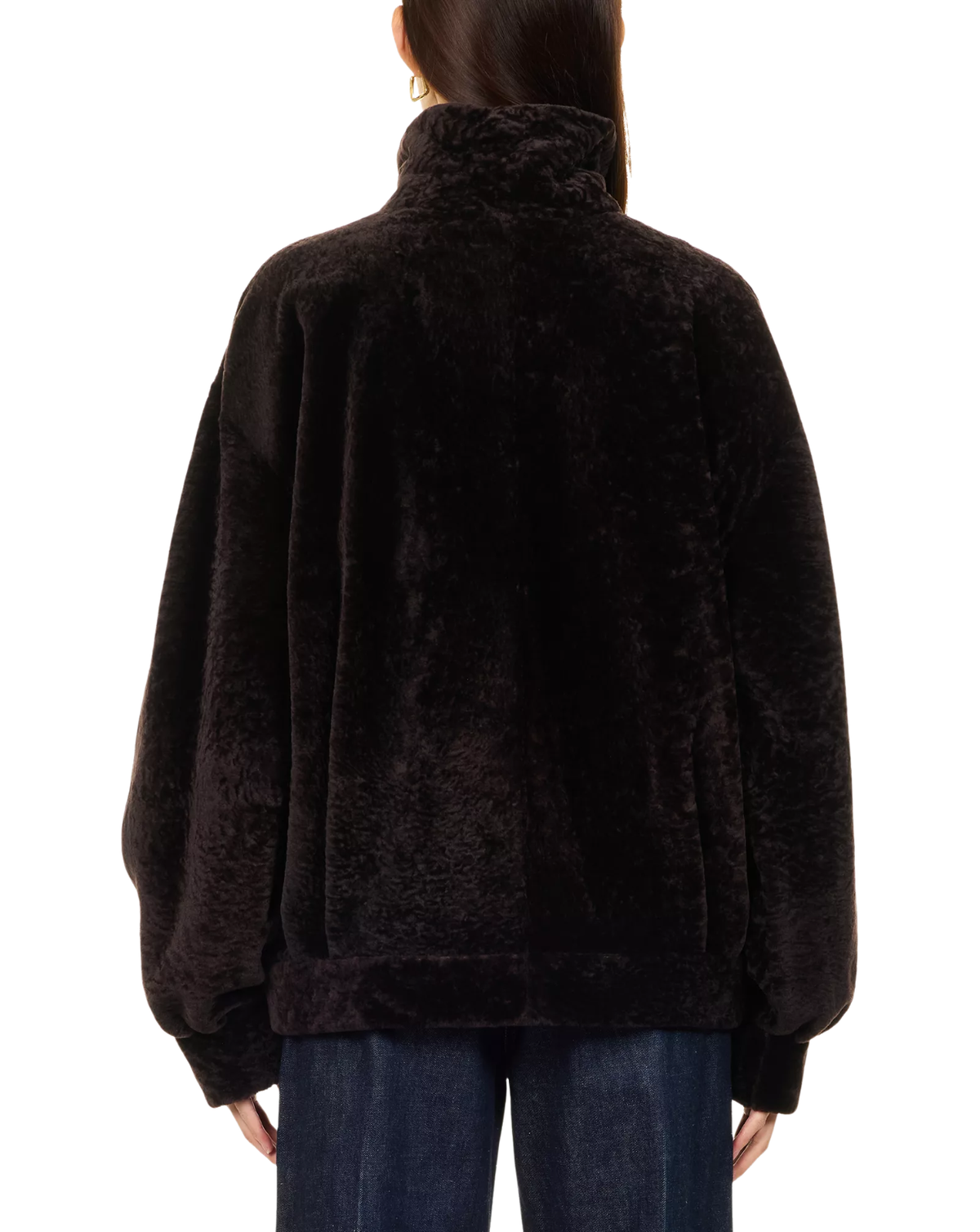 A person viewed from the back wearing a dark brown plush faux-fur jacket with a high collar and voluminous sleeves, paired with blue jeans against a plain white background.