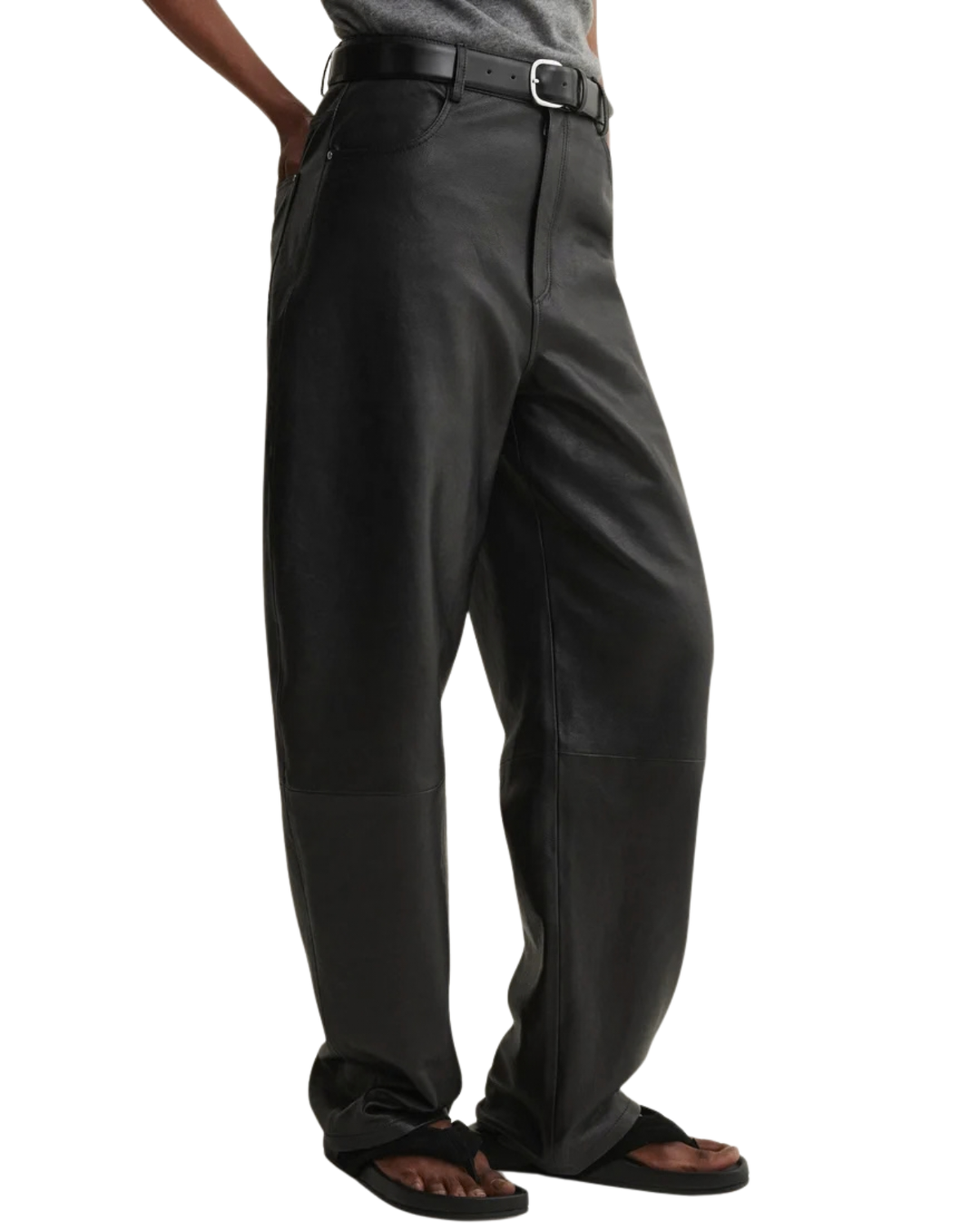 Black wide-leg pants with a relaxed, baggy fit, modeled on a person wearing a gray shirt, black belt, and black sandals against a white background.