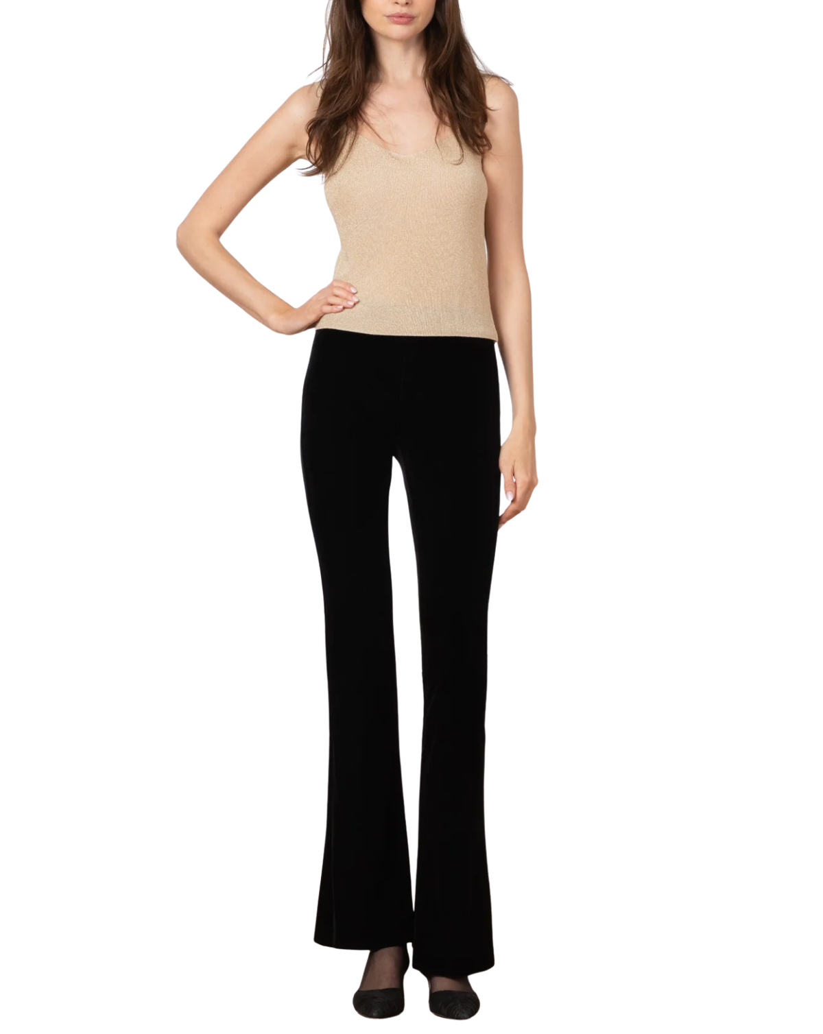 A woman modeling a sleeveless beige knit top and black flared pants against a plain white background.