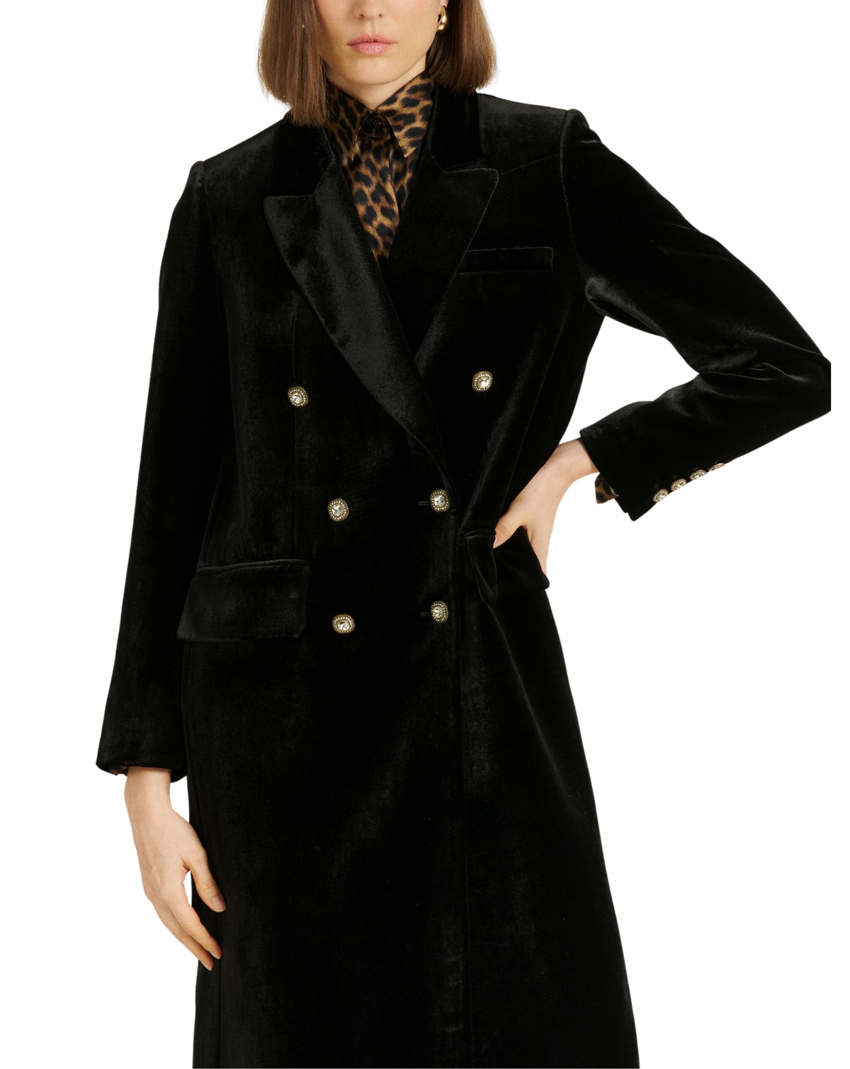 A model wearing a black velvet double-breasted coat with gold buttons, styled with a leopard print scarf against a plain white background.
