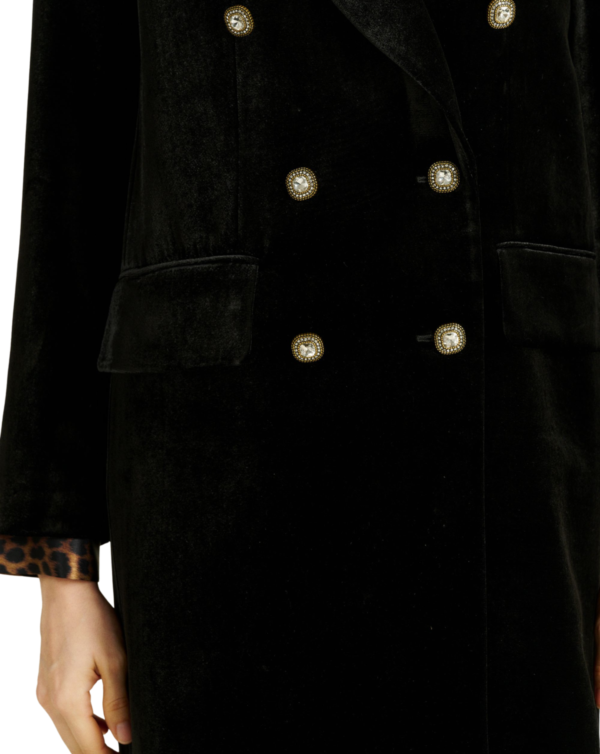 Close-up of a black velvet double-breasted coat with ornate gold-tone buttons and a leopard-print cuff visible at the sleeve.
