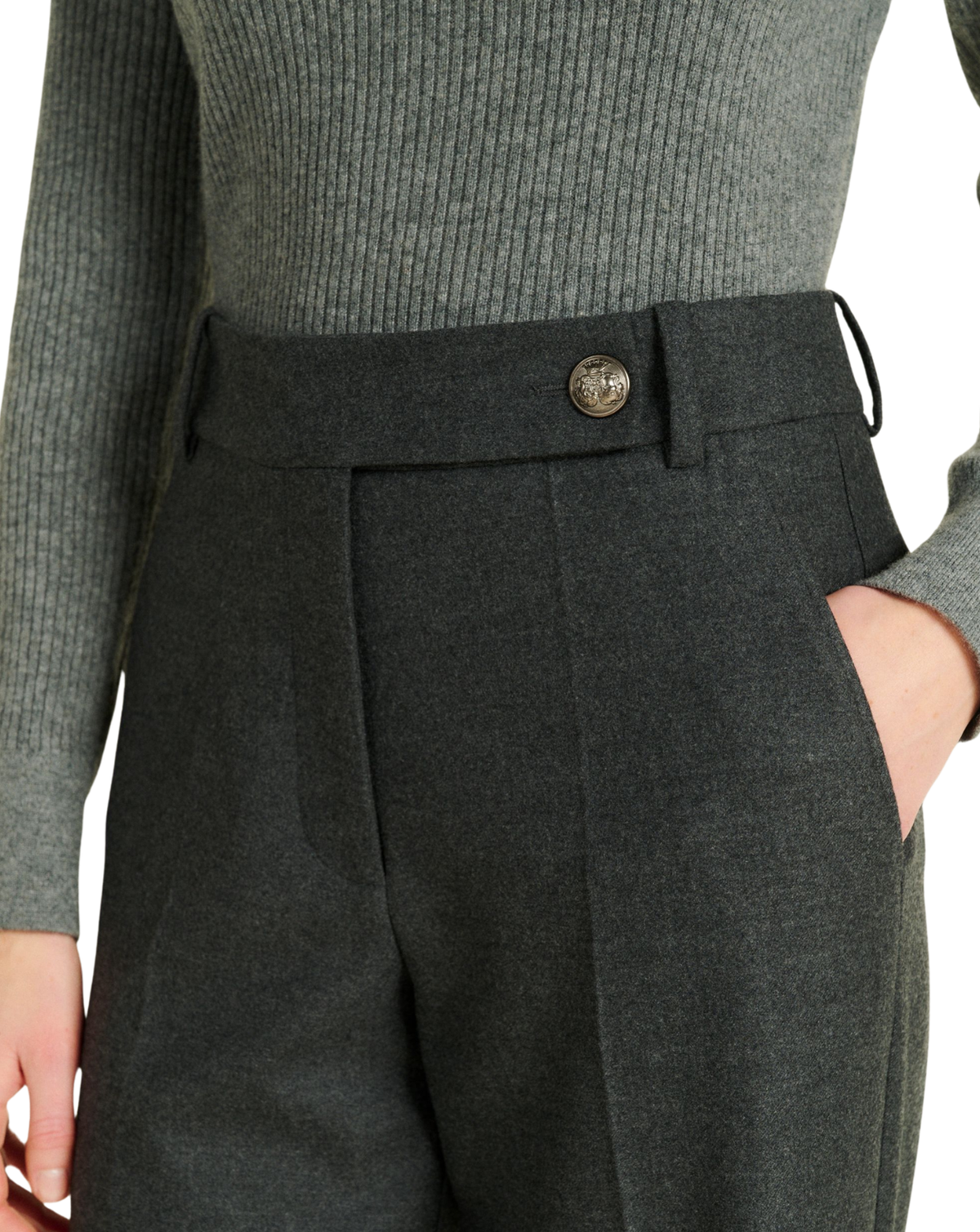 Close-up of a person wearing dark charcoal gray wool trousers with a matching waistband belt and a single decorative button, paired with a ribbed gray sweater.