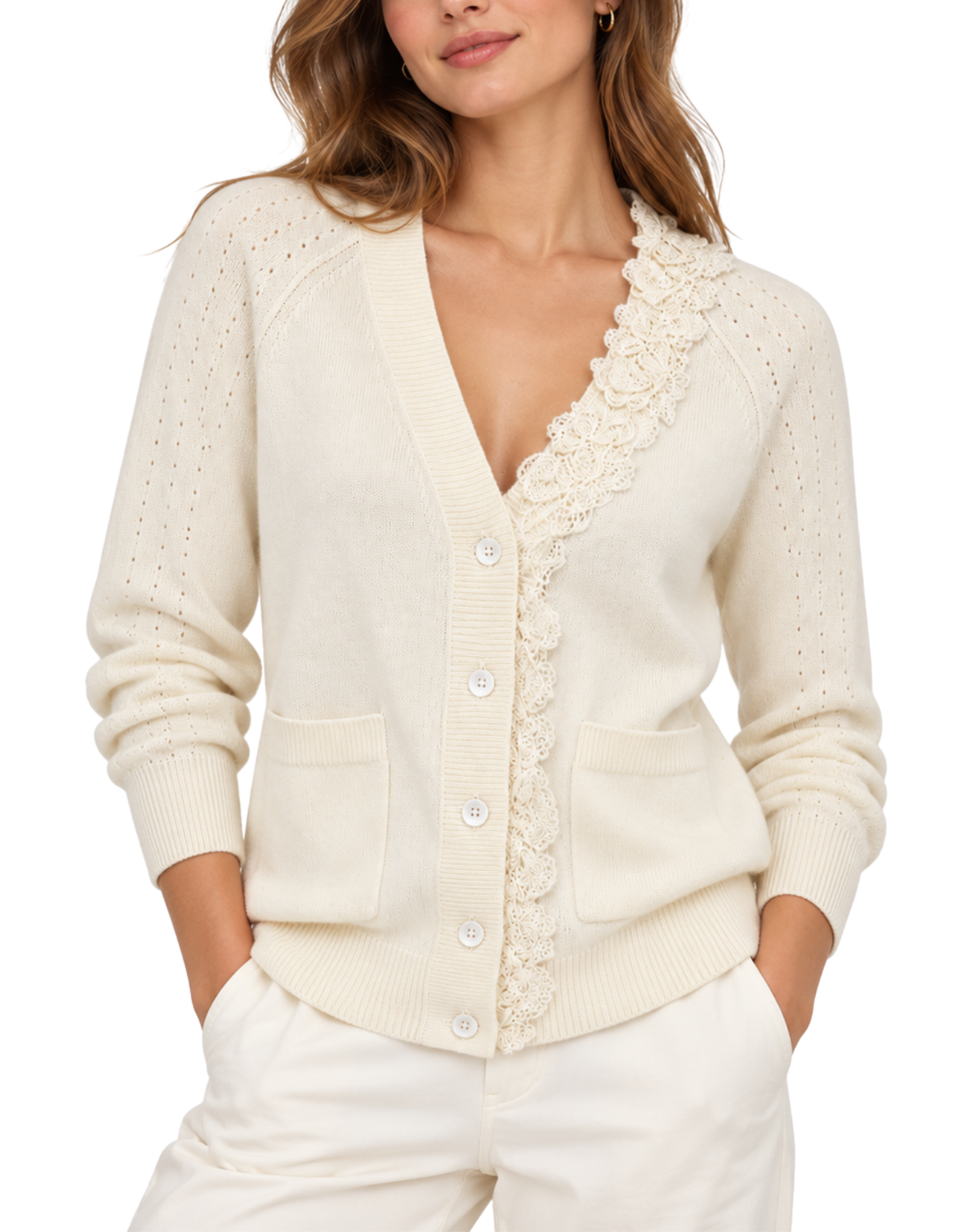 A woman wearing a cream-colored knit cardigan sweater with a scalloped floral lace trim down the front, paired with cream pants, against a plain white background.