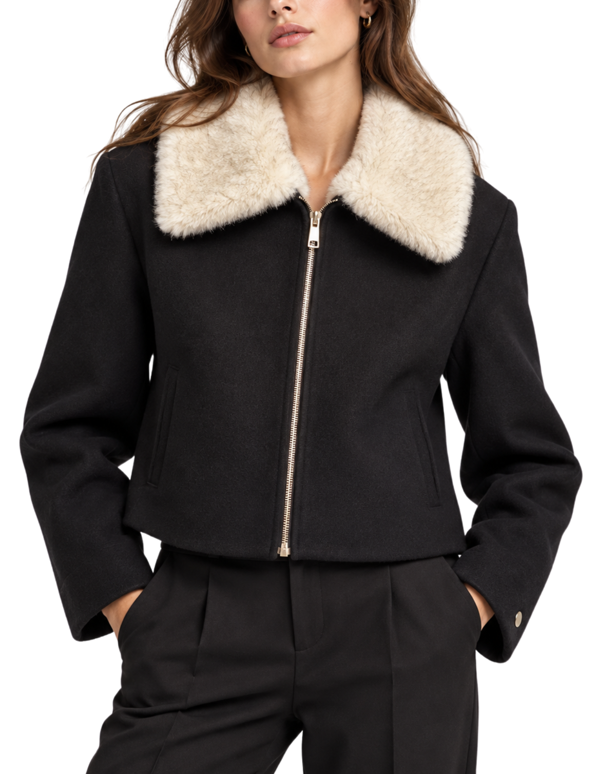 A woman wearing a black cropped jacket with a large cream-colored faux fur collar, paired with black trousers, against a plain white background.