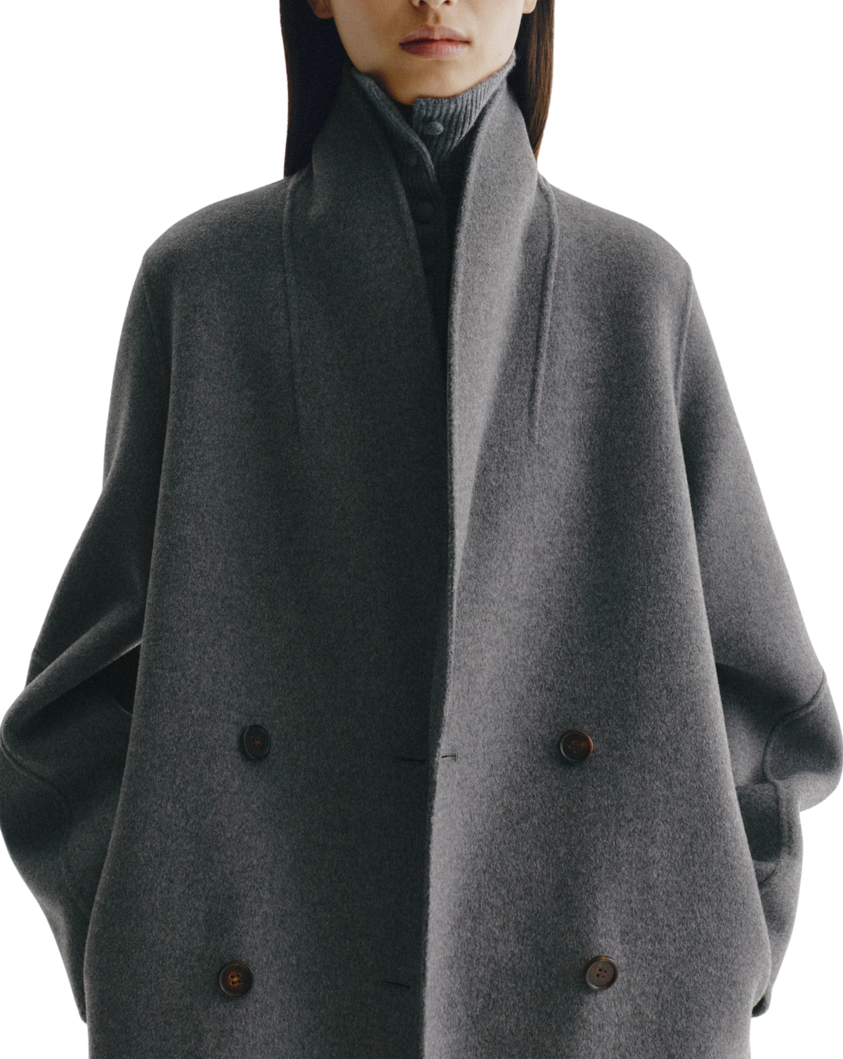 A close-up of a model wearing a dark gray shawl collar double-breasted coat over a dark gray turtleneck sweater, against a plain white background.