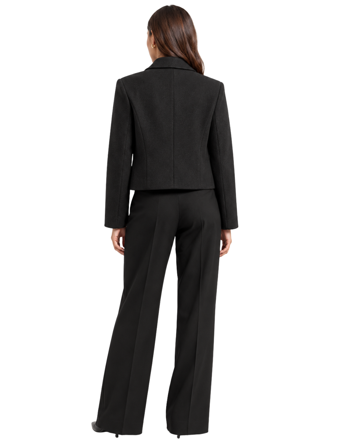 A woman shown from the back wearing a black tailored suit with a cropped jacket and wide-leg trousers, photographed against a plain white studio background.