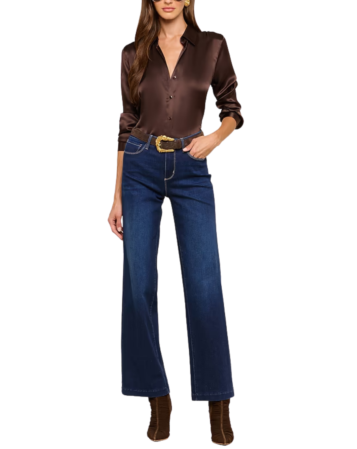 A woman modeling a dark brown satin button-up shirt and dark blue wide-leg jeans with a gold buckle belt, paired with brown suede ankle boots, against a plain white background.