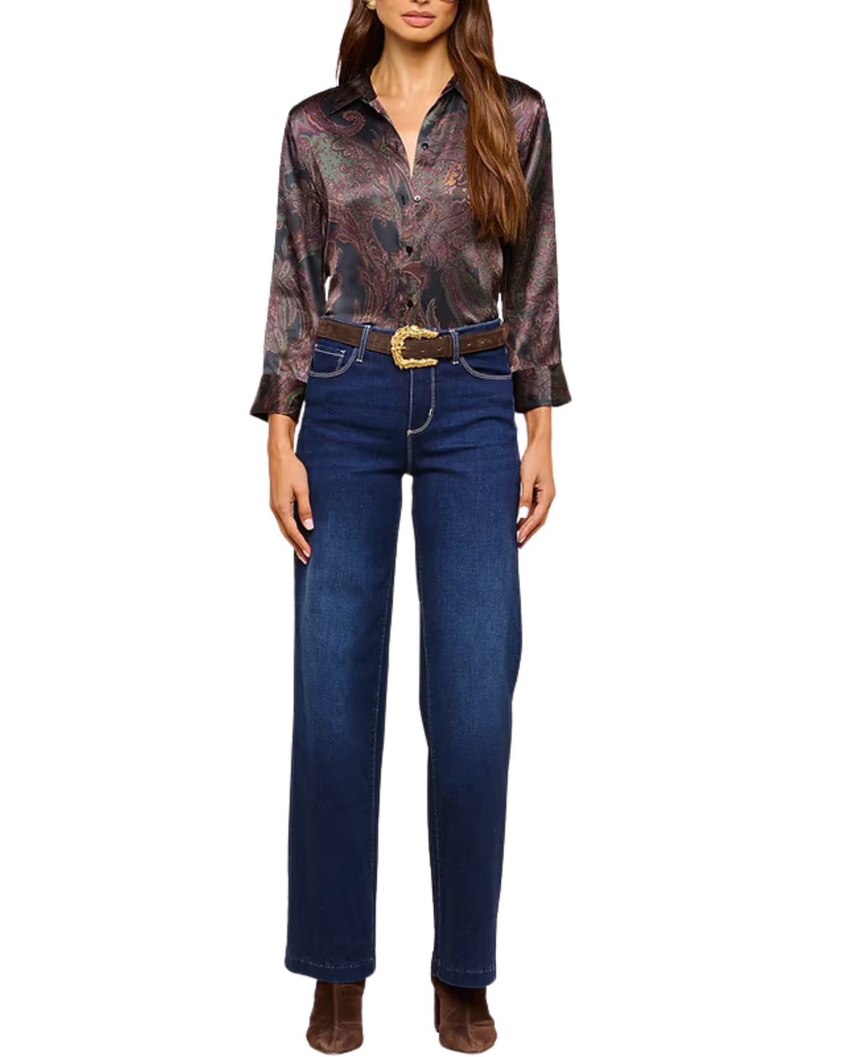 A woman modeling a long-sleeve button-up shirt with a dark paisley pattern in brown, purple, and gold, paired with dark blue jeans, a brown belt, and brown boots against a plain white background.