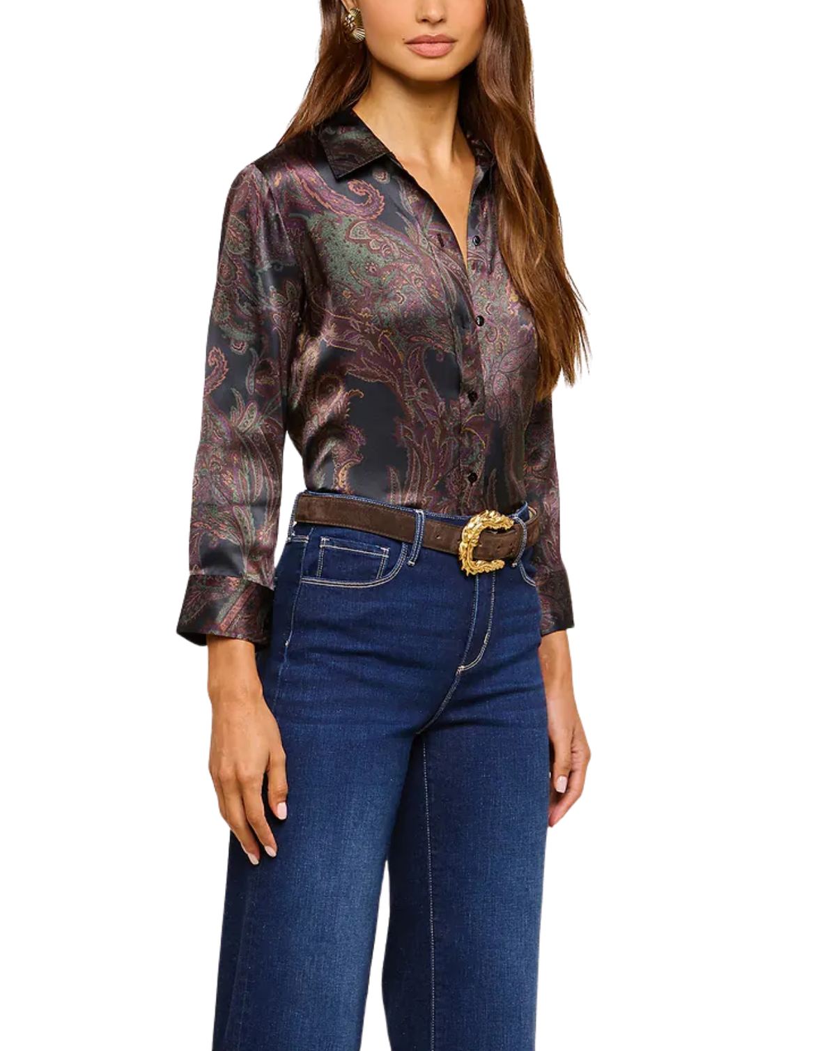 A woman wearing a long-sleeve button-up shirt with a dark paisley pattern in black, brown, and muted red tones, tucked into dark blue jeans with a brown belt featuring a gold buckle.