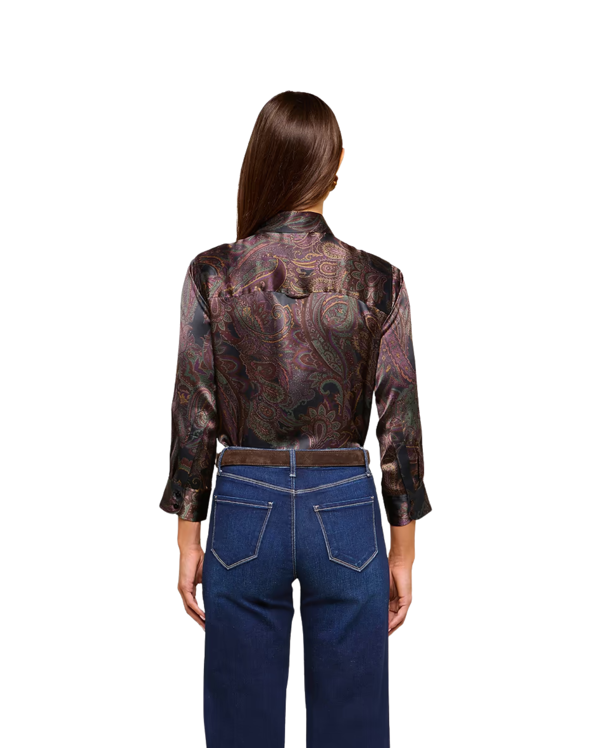 A woman viewed from the back wearing a long-sleeve satin shirt with a brown, purple, and gold paisley pattern, tucked into dark blue jeans with a brown belt.