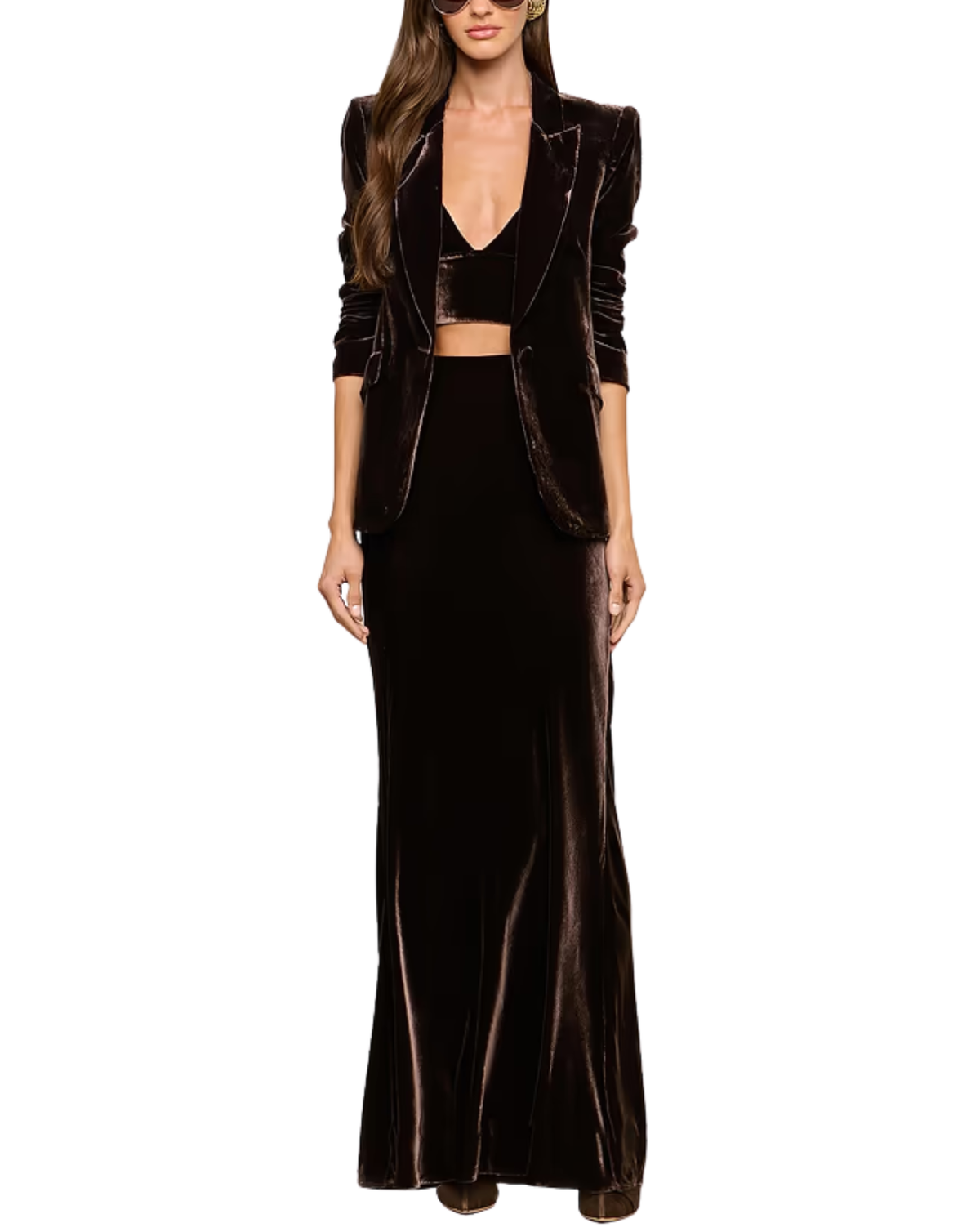A model wearing a three-piece dark brown velvet outfit consisting of a long-sleeve blazer, a matching crop top, and a floor-length skirt, set against a plain white background.