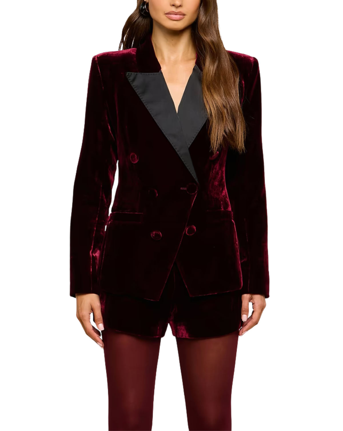 A woman wearing a deep burgundy velvet blazer with contrasting black satin lapels, matching velvet shorts, and burgundy tights, shown against a plain white background.