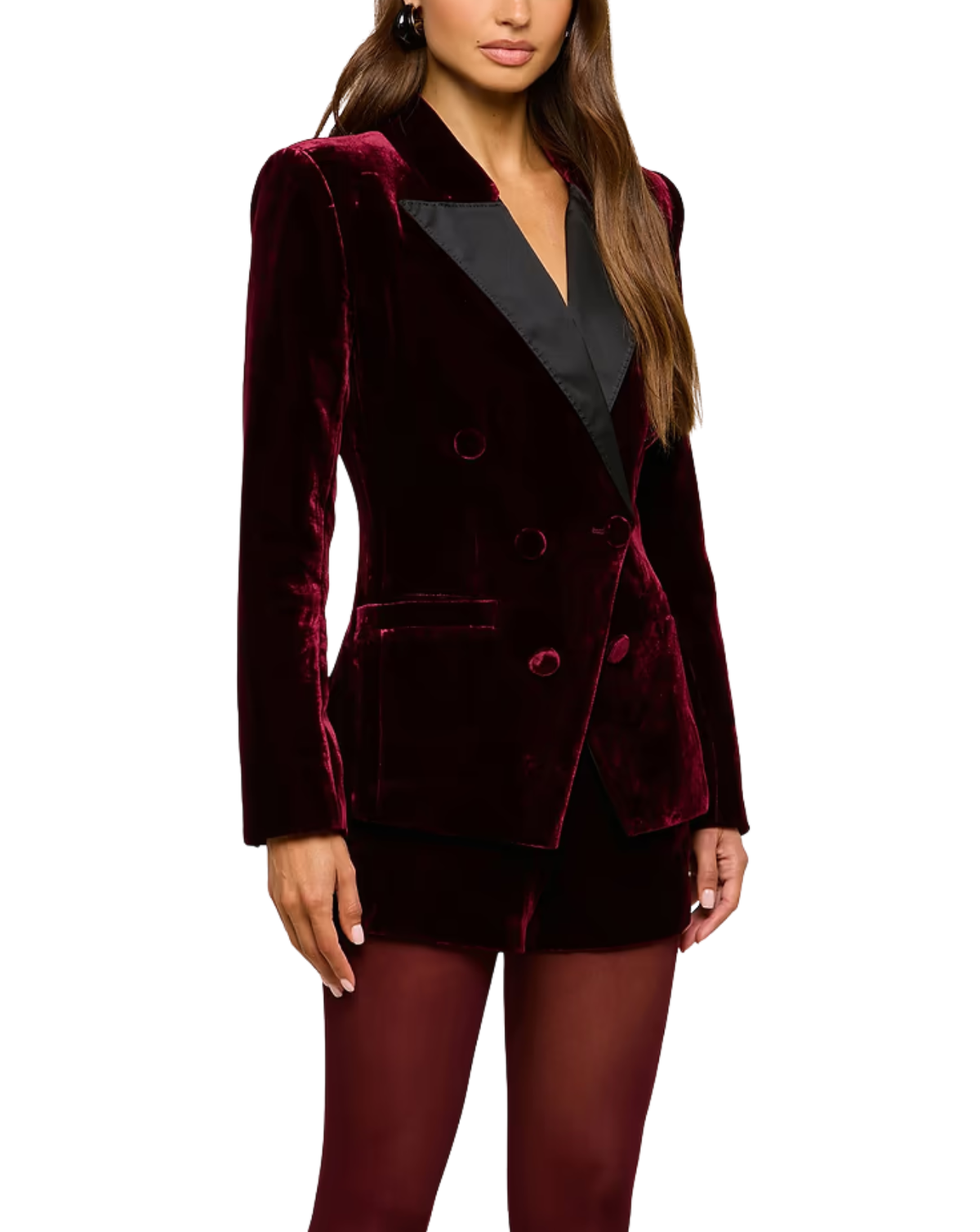 A woman wearing a double-breasted velvet blazer in deep burgundy with black satin lapels, paired with matching burgundy shorts and tights, against a plain white background.