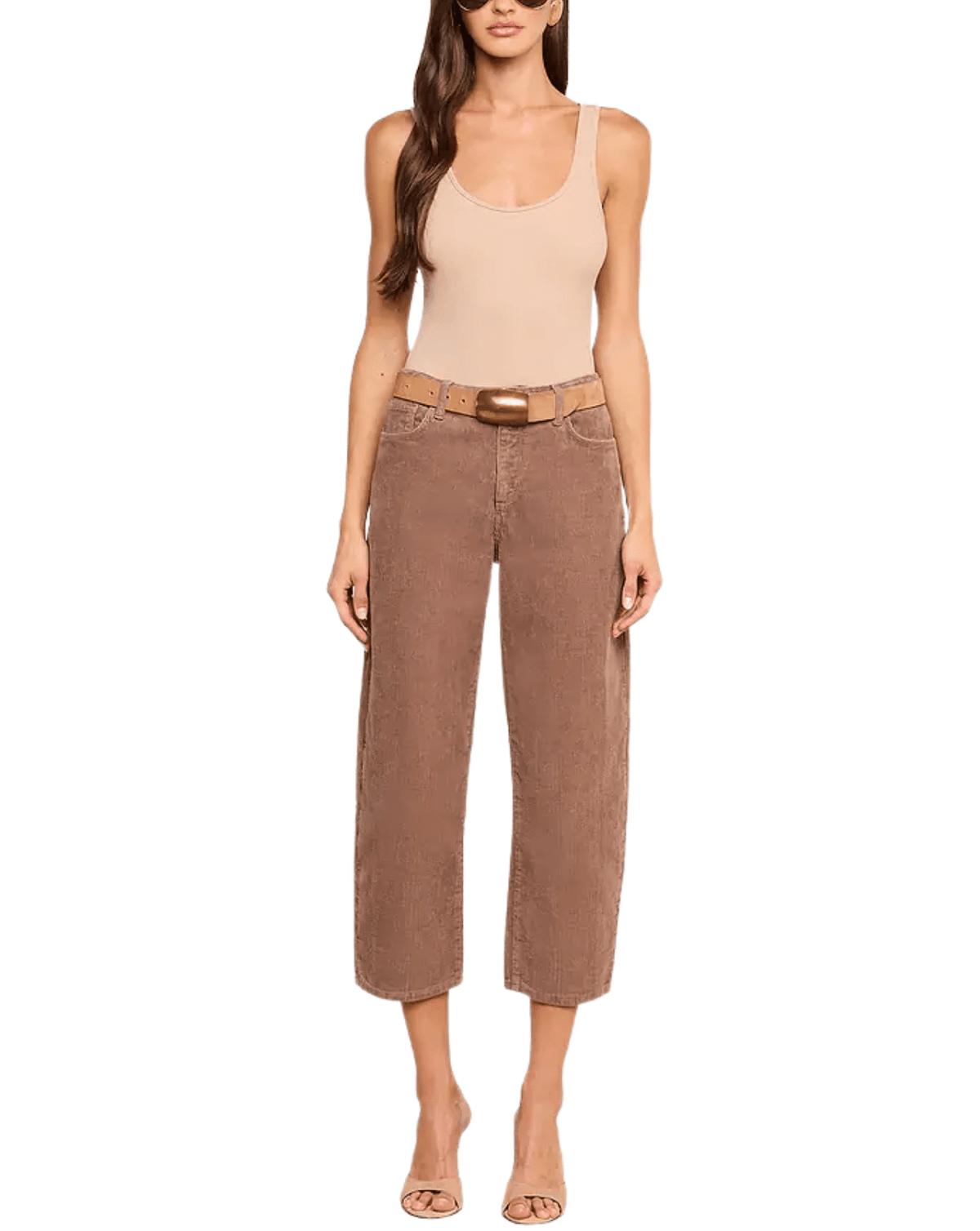 A model wearing a pair of wide-leg cropped brown pants with a tan belt, paired with a beige tank top and nude heels, set against a plain white background.