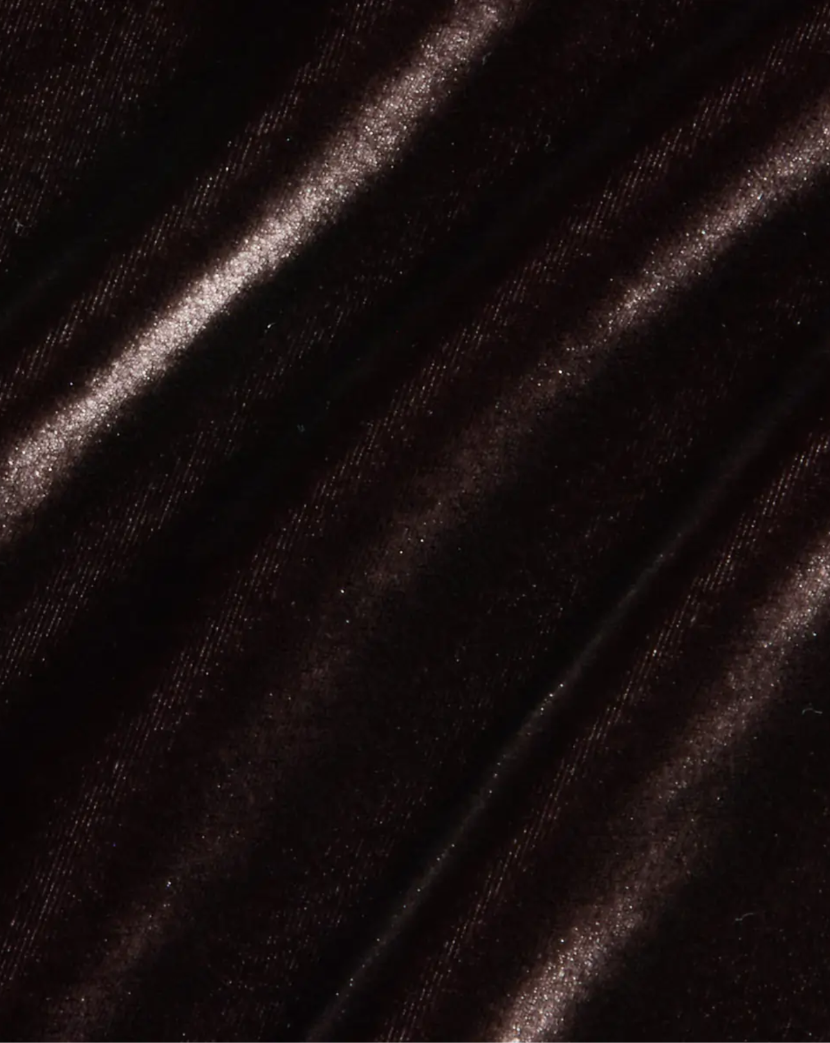 A close-up of dark brown velvet fabric with a soft, lustrous sheen and diagonal folds.
