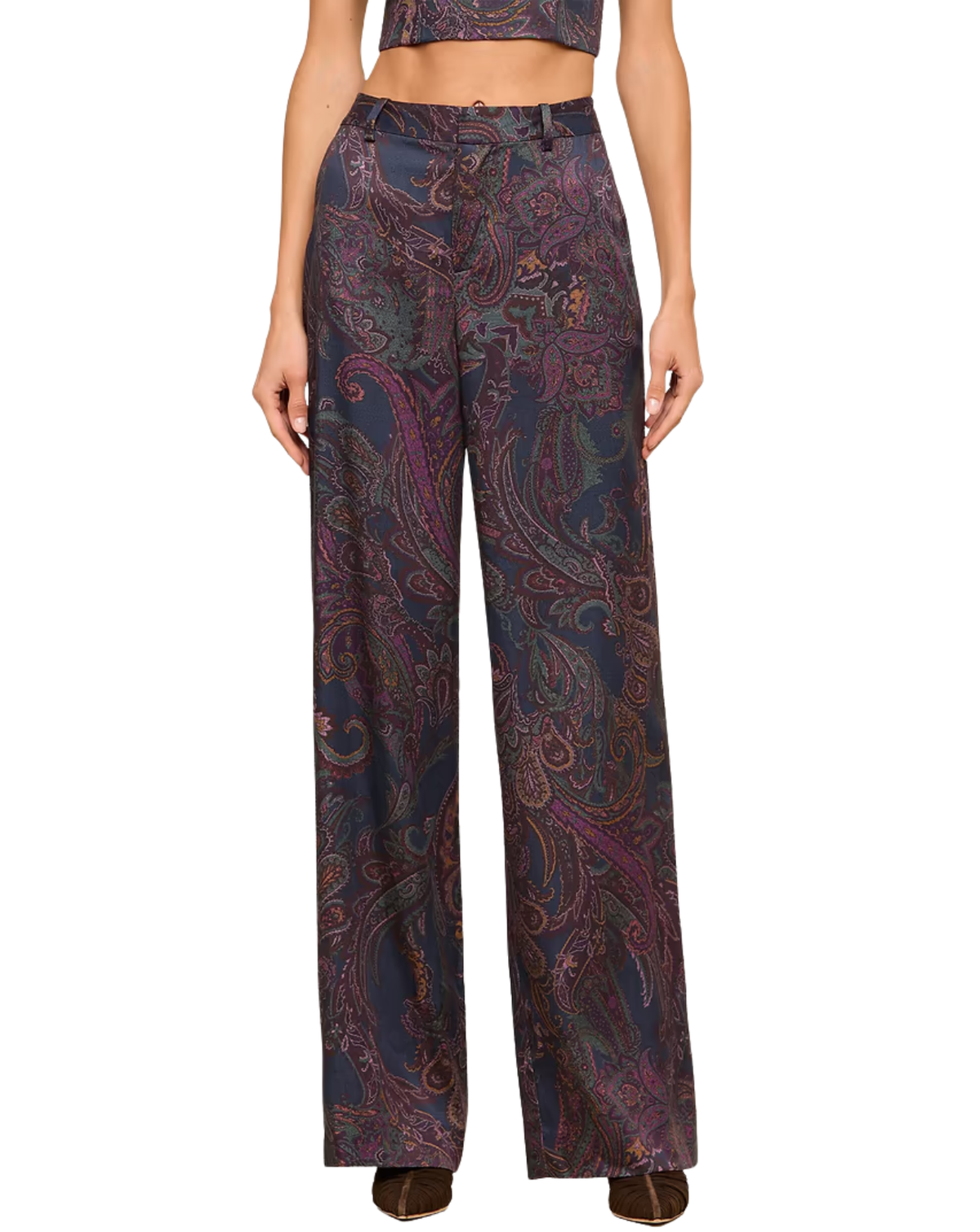 A model is wearing high-waisted, wide-leg trousers featuring an intricate paisley pattern in navy blue, purple, and gold. The image is cropped from the chest down, set against a plain white background.