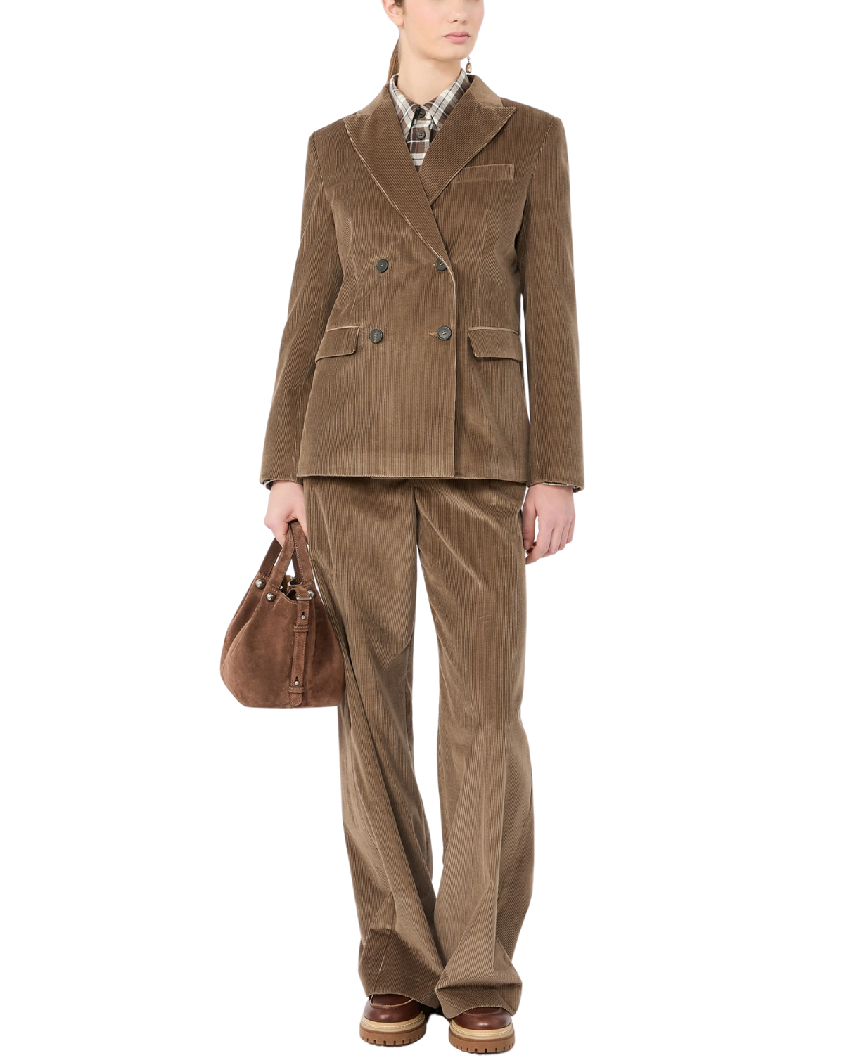 A model wearing a matching brown corduroy blazer and trousers suit, styled with a patterned shirt, brown leather loafers, and a brown leather handbag, set against a plain white background.