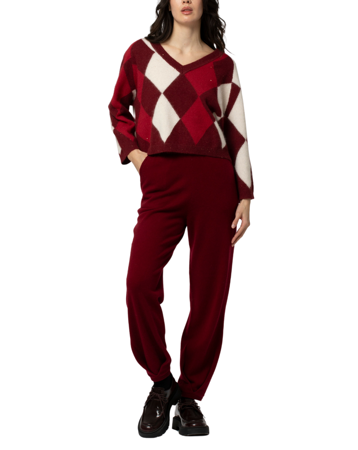 A model wearing a burgundy and cream argyle sweater with matching burgundy jogger pants and black shoes, shown against a plain white background.