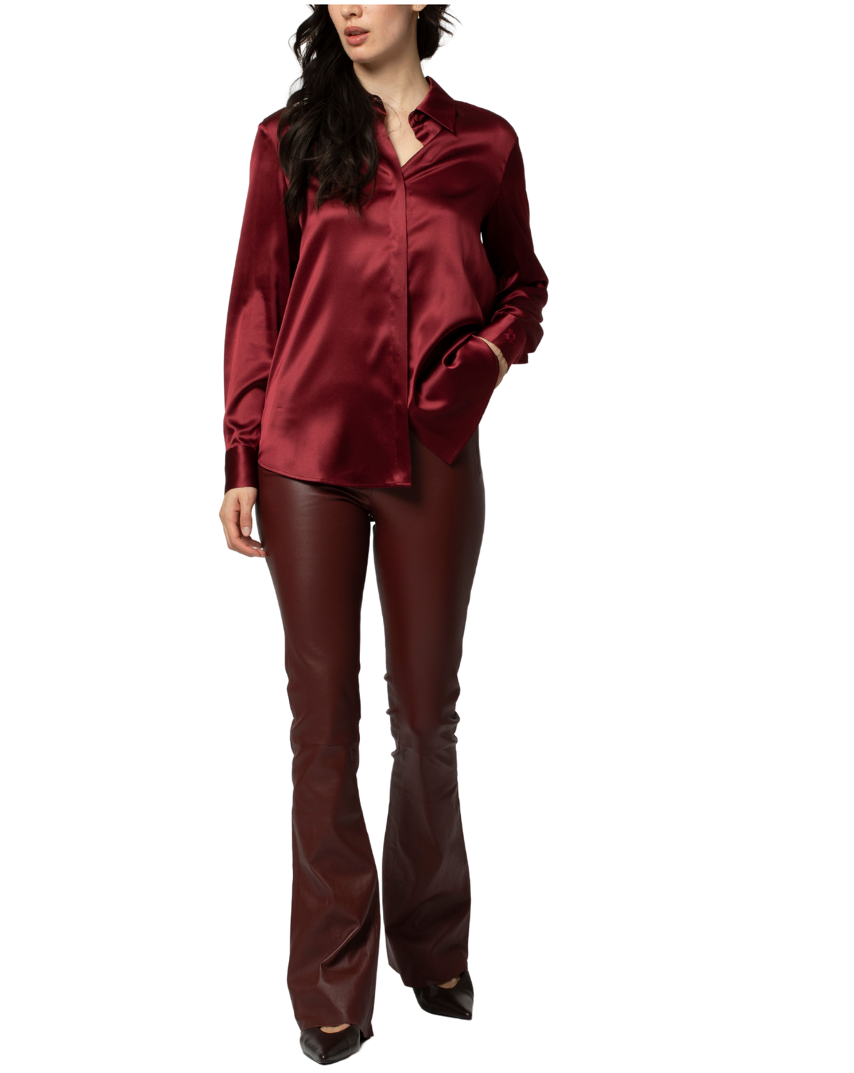 A woman modeling a matching burgundy satin button-up shirt and faux leather flare pants against a plain white background.