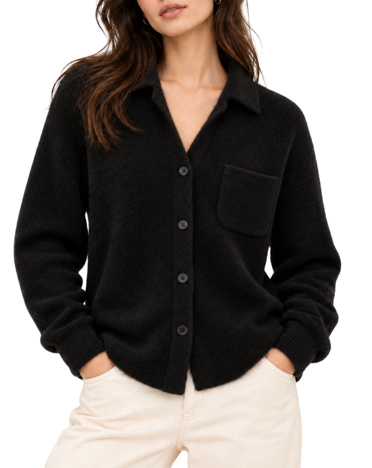 A woman wearing a black knit button-front cardigan with a collar and chest pocket, paired with light cream pants, against a plain white background.