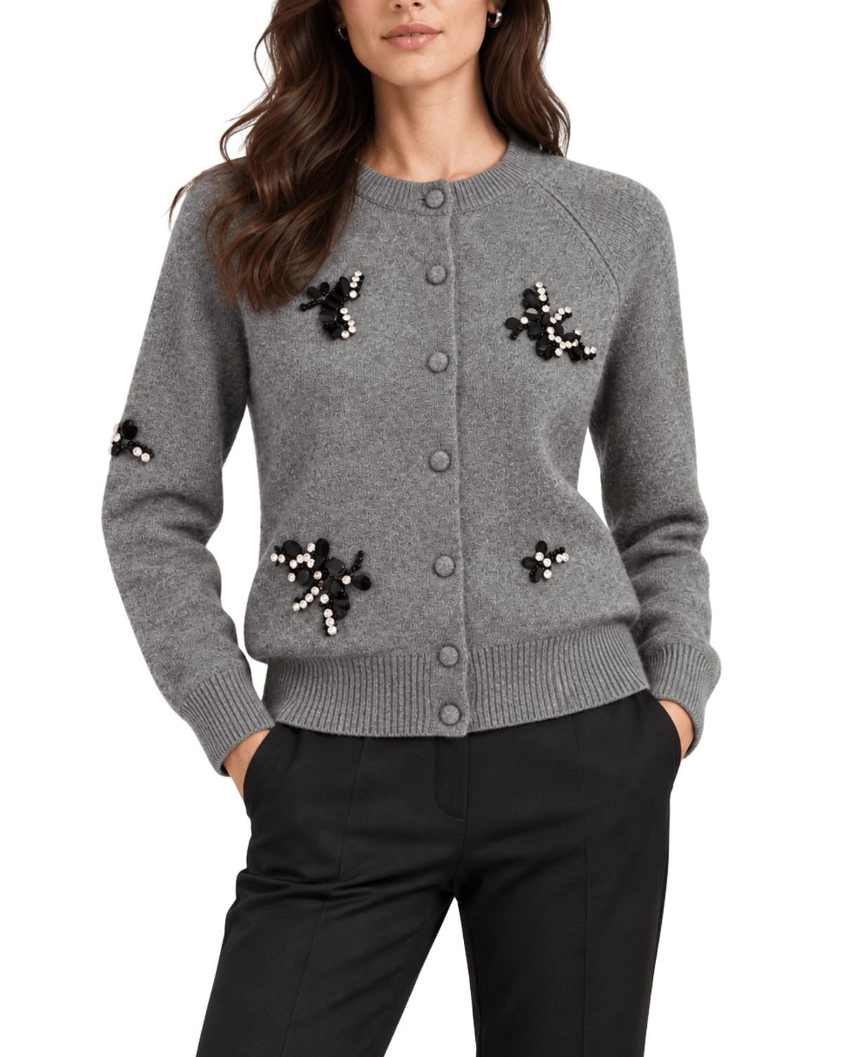 A woman wearing a gray button-front knit cardigan with black and white beaded floral embellishments, paired with black pants, against a plain white background.