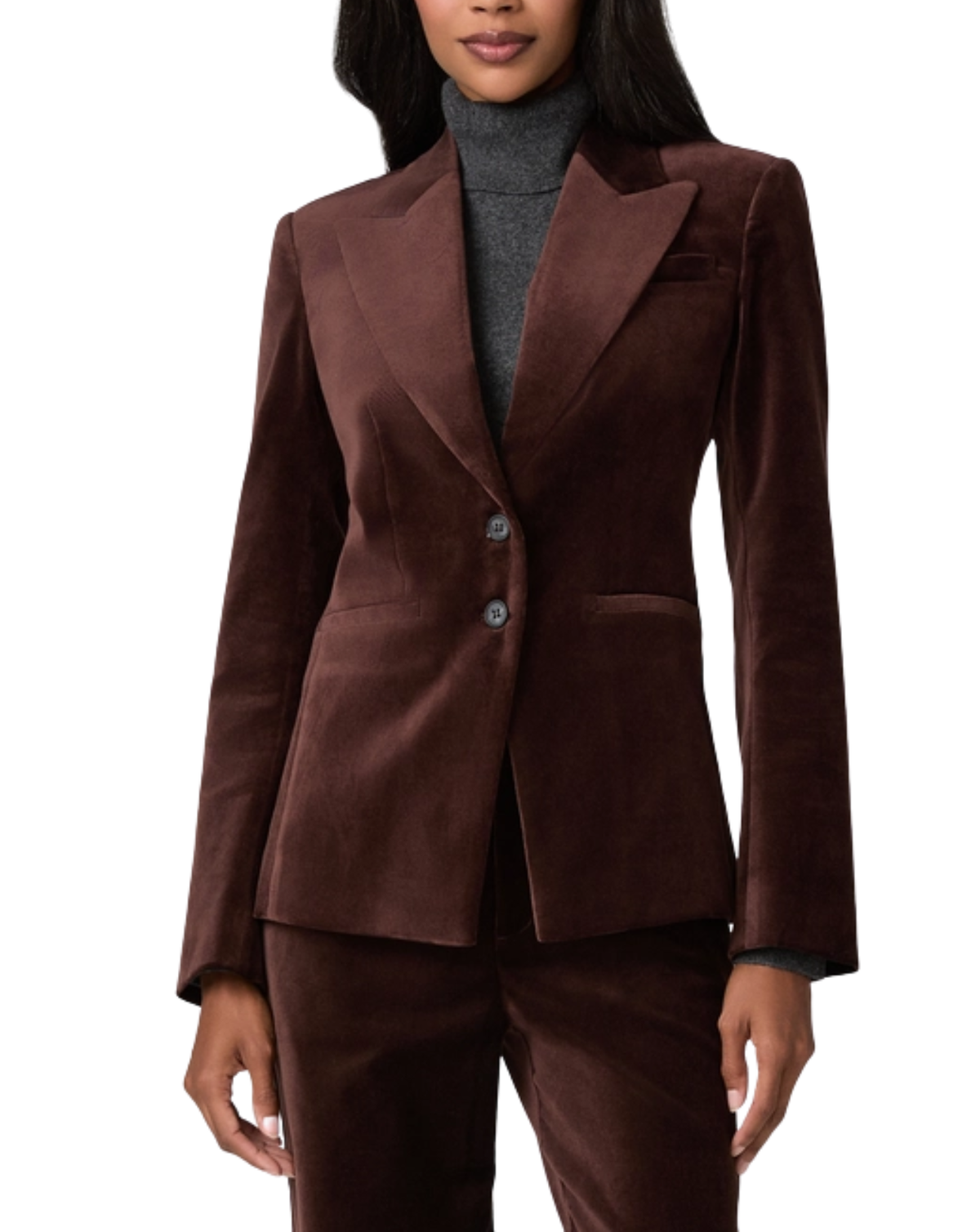 A woman wearing a dark brown velvet blazer and matching trousers over a gray turtleneck sweater, shown against a plain white background.