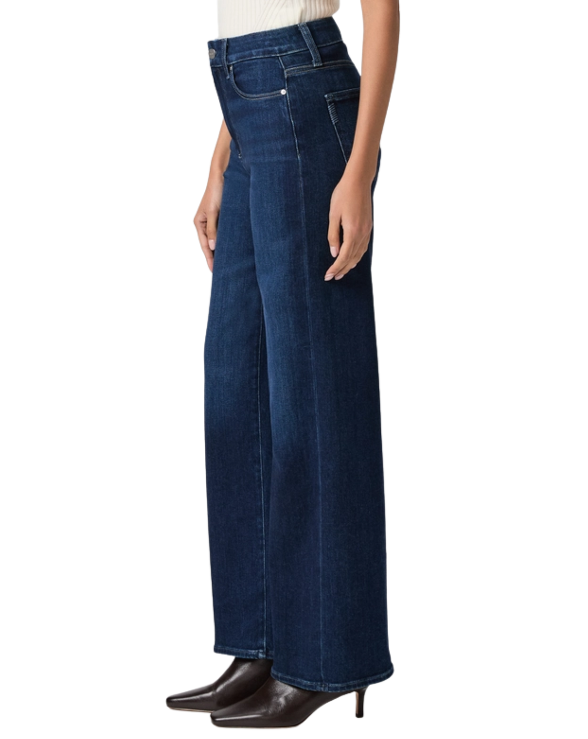 A model wearing dark blue wide-leg denim jeans, styled with a cream top and dark brown pointed-toe heels, shown from the waist down on a white background.