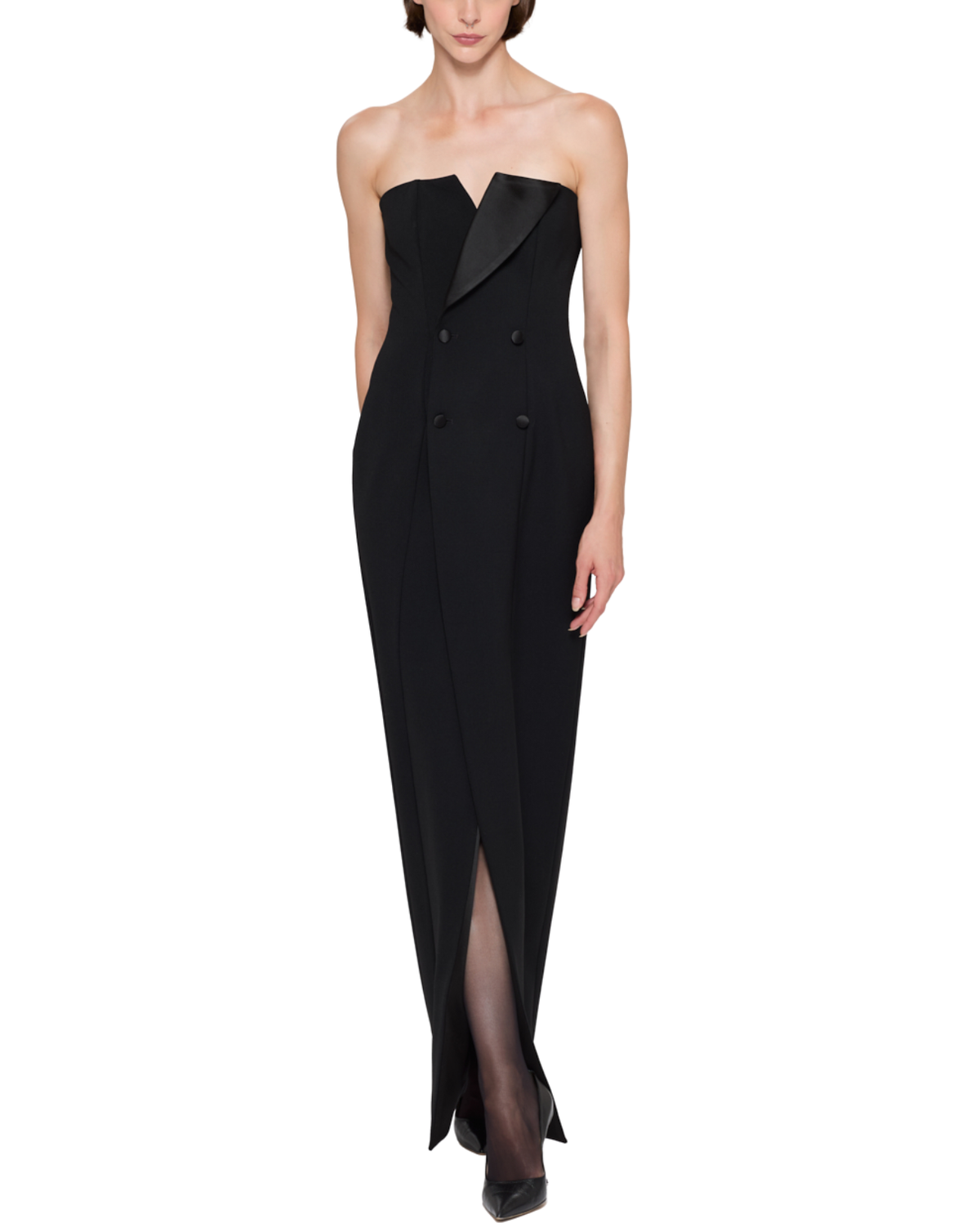 A model wearing a black strapless double-breasted gown with a satin lapel and thigh-high slit, photographed against a plain white background.