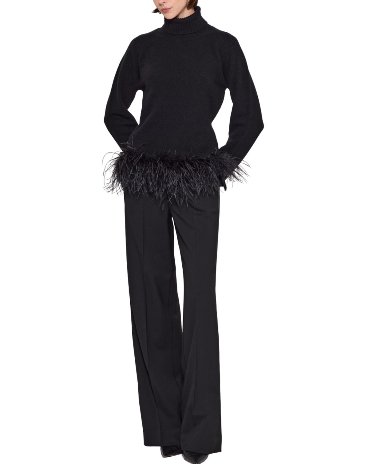 A model wearing a black long-sleeve mock-neck top with a black feather trim at the hem, paired with black wide-leg trousers, against a plain white background.