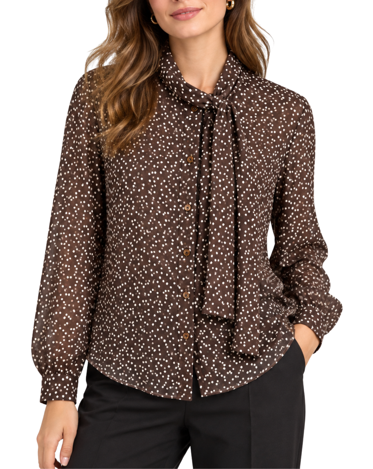 A woman wearing a brown long-sleeve blouse with a white ditsy print and a tie-neck detail, paired with black pants, against a plain white background.