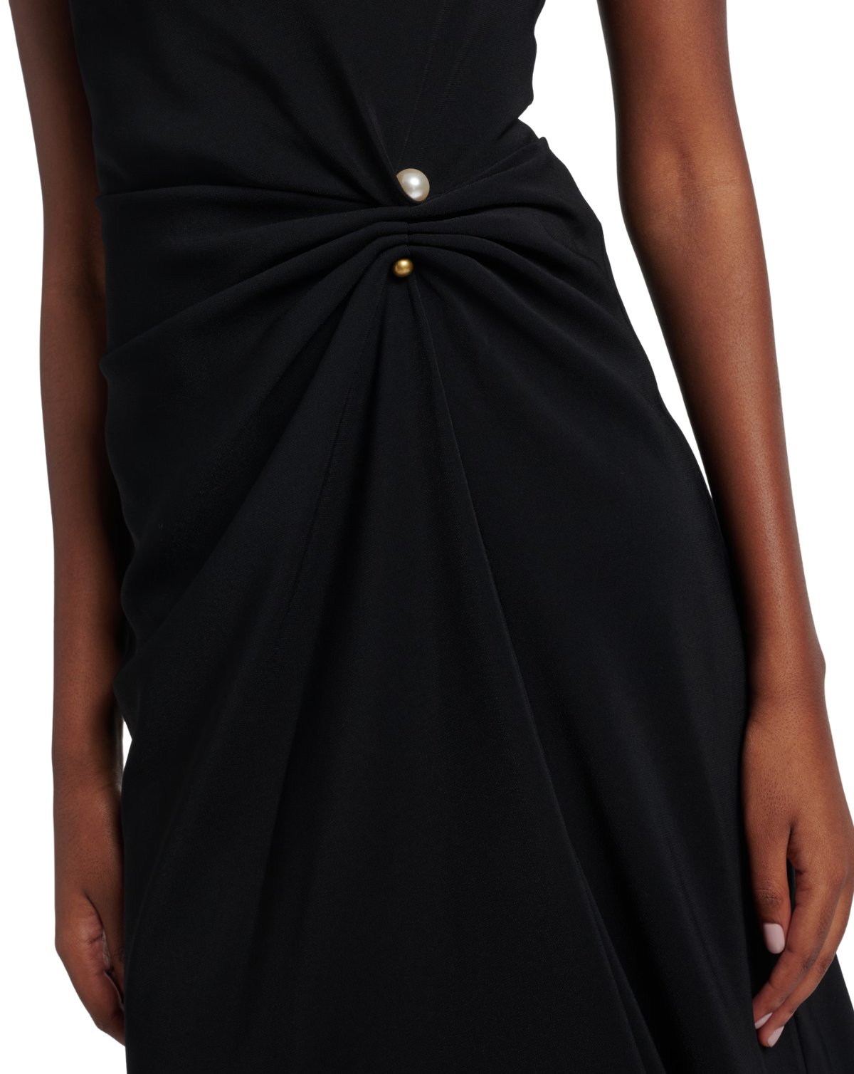 Close-up of a black dress with a twisted waist detail, featuring a pearl-like white button and a small gold button, worn by a model.