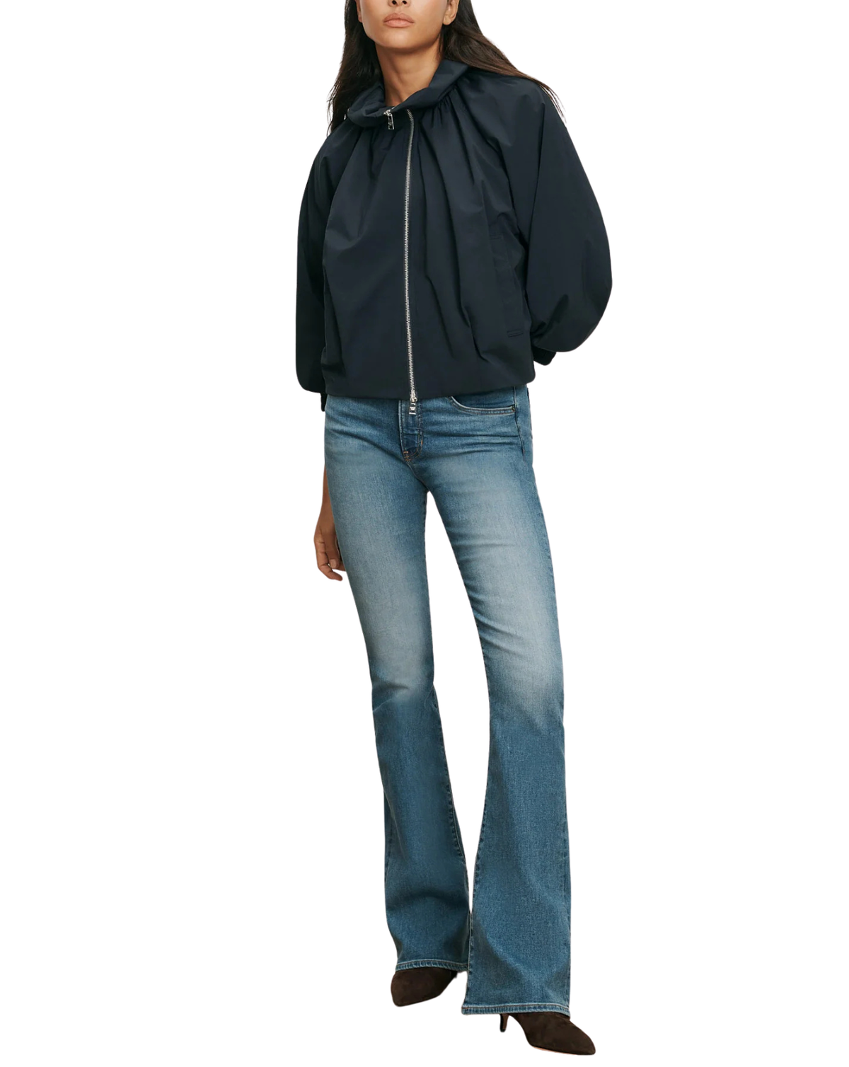 A model wearing a black hooded zip-up jacket with voluminous sleeves and blue flare jeans, shown against a plain white background.