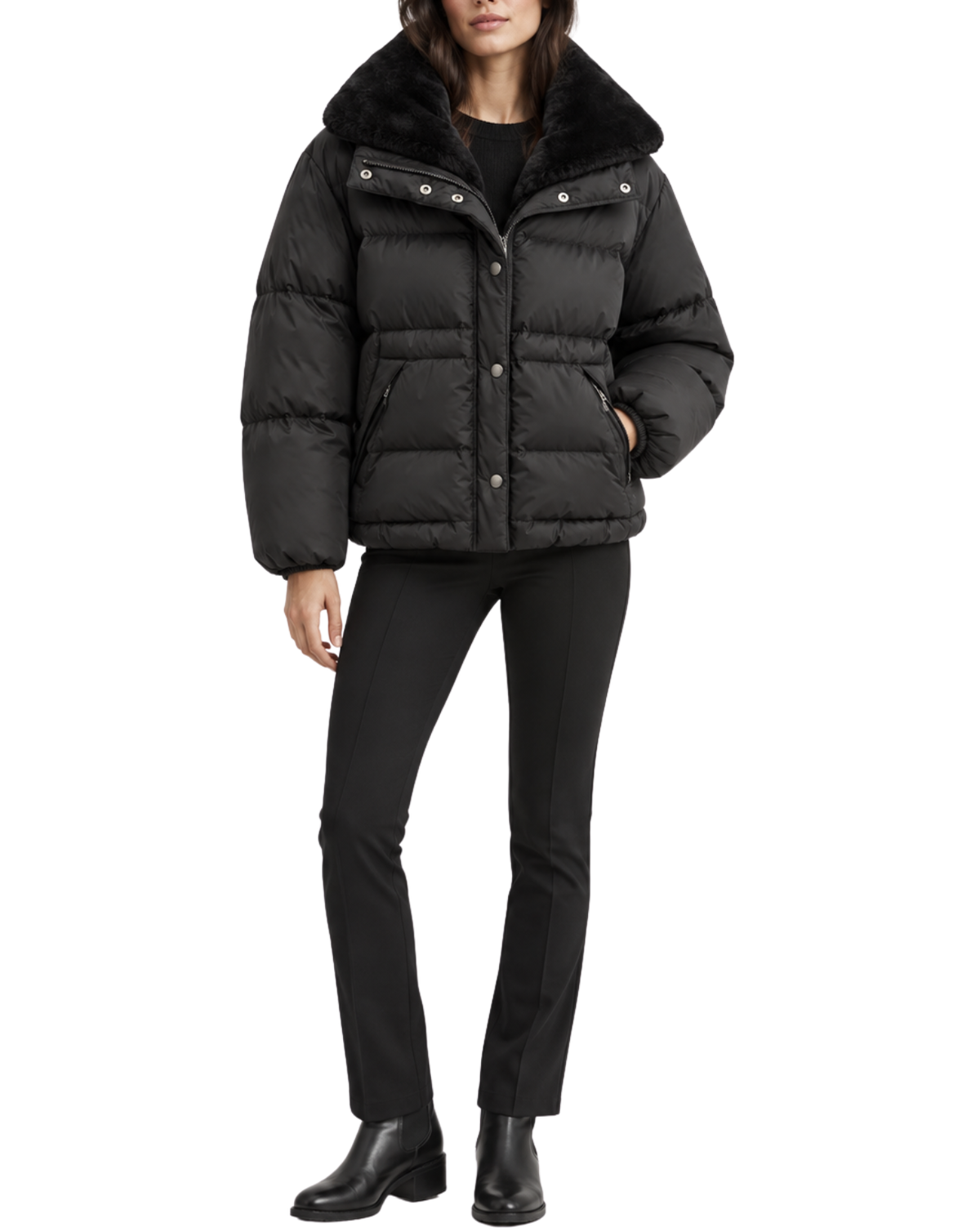 A model wearing a black puffer jacket with a black faux-fur collar, paired with black pants and black boots, against a plain white background.
