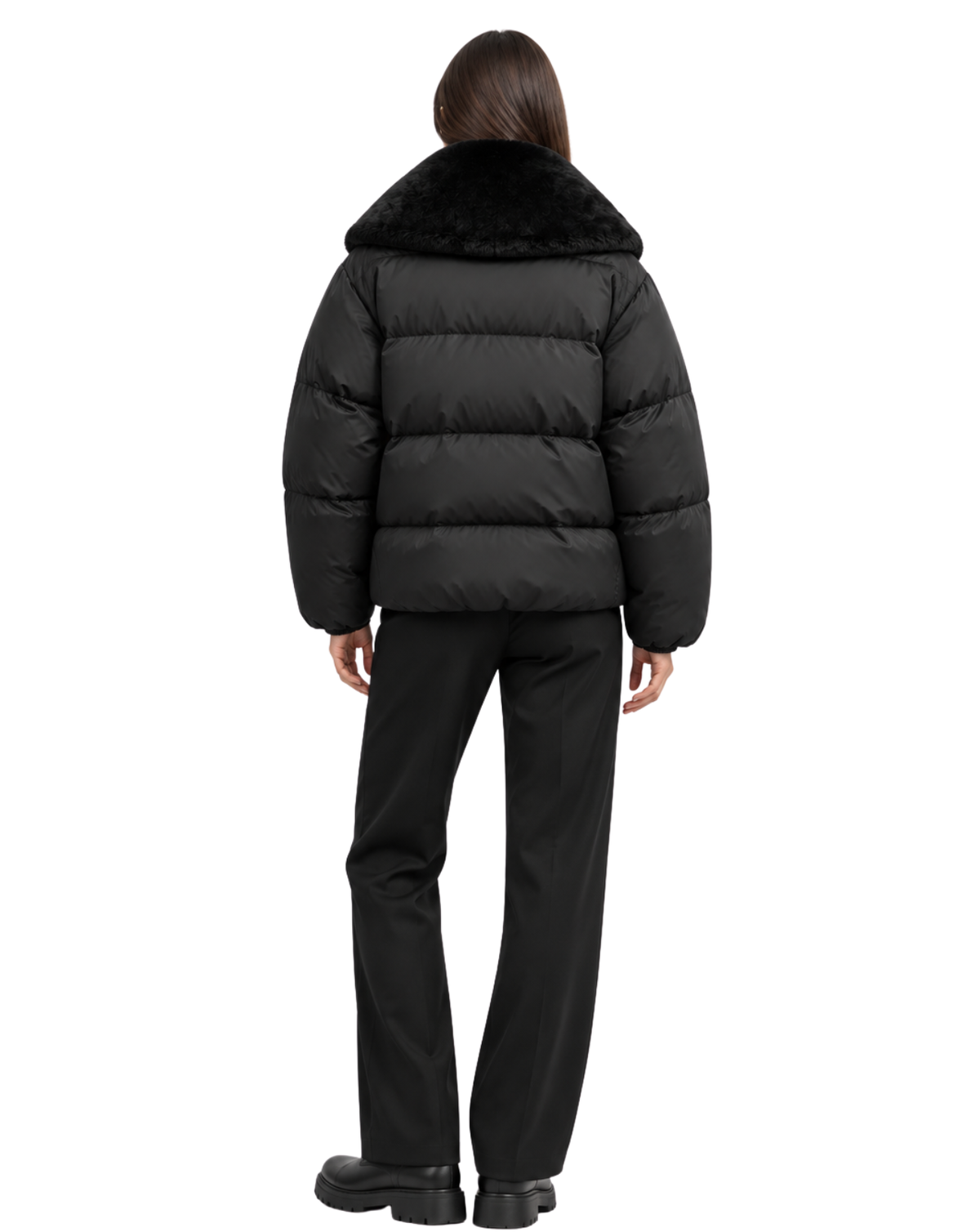A model viewed from the back wearing a black puffer jacket with a contrasting black faux-fur collar, paired with black trousers and black shoes, on a solid white background.