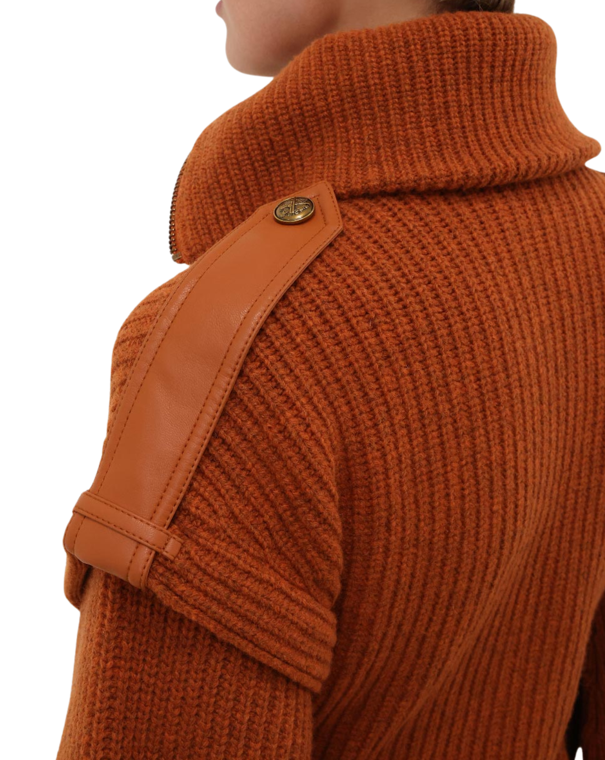 Close-up of a person wearing a rust-orange ribbed knit turtleneck sweater with a tan shoulder strap detail and a gold-tone button.