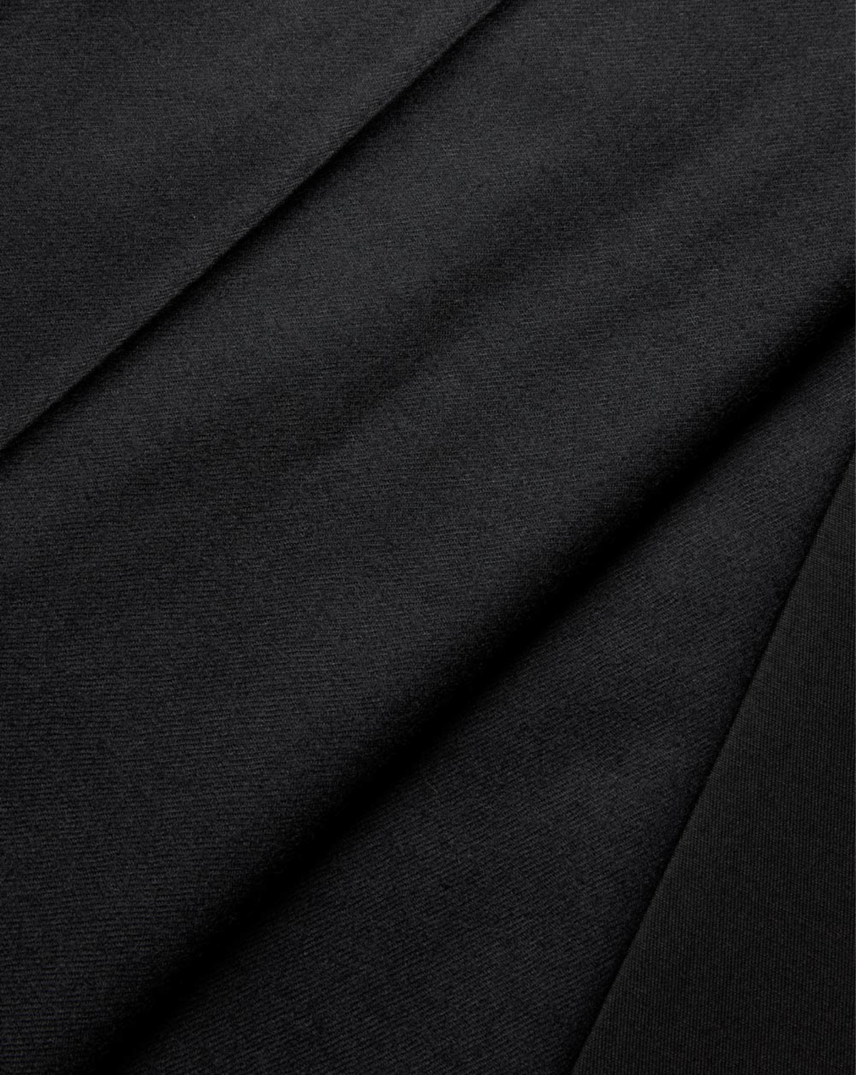 A close-up of draped black fabric with soft diagonal folds and a fine woven texture.