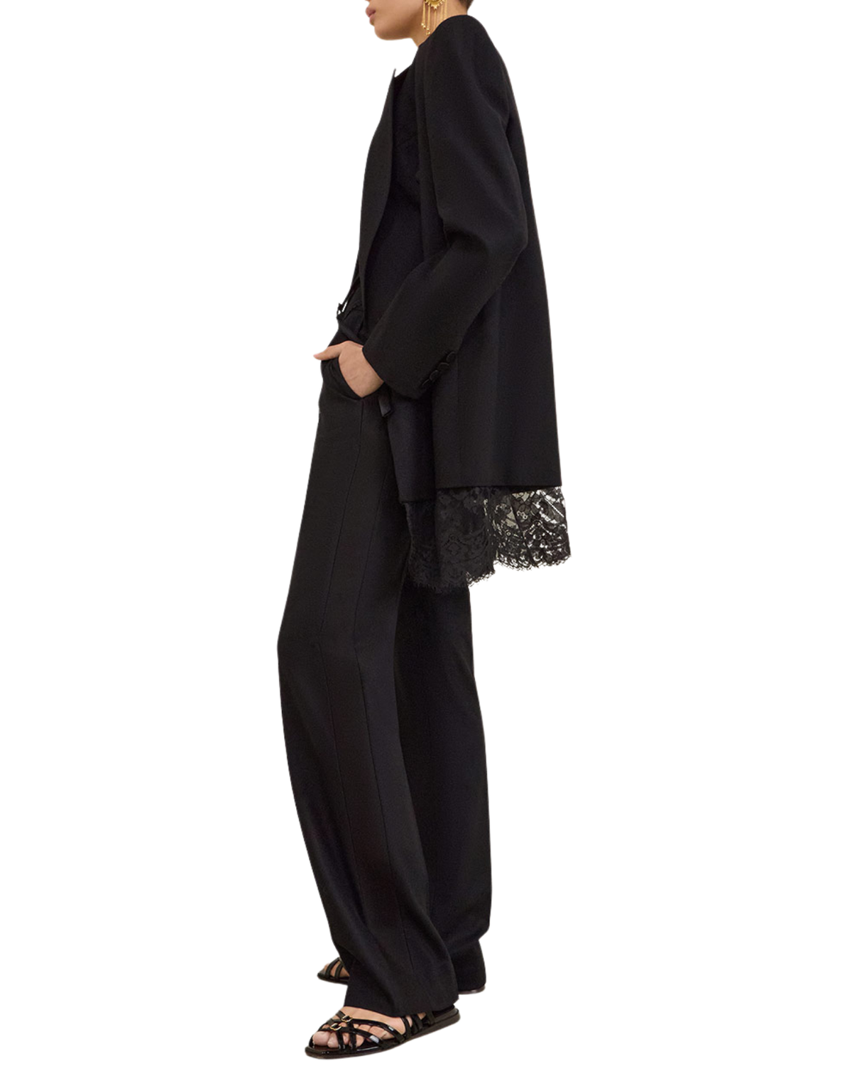 A model shown in profile wearing a black wide-leg pants suit with a matching black blazer draped over the shoulders. The blazer features a black lace trim along the hem and sleeve cuffs.
