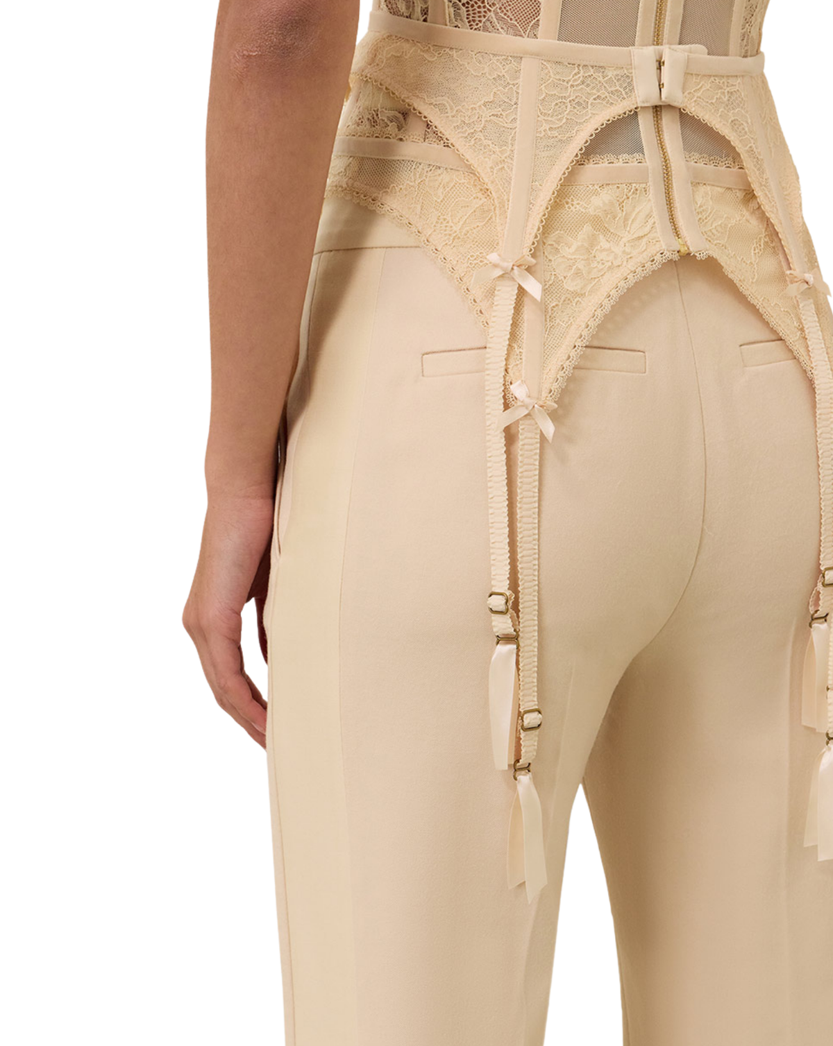 Close-up of a model wearing high-waisted beige pantyhose with a lace waist panel, front garter straps, and side ties against a plain white background.